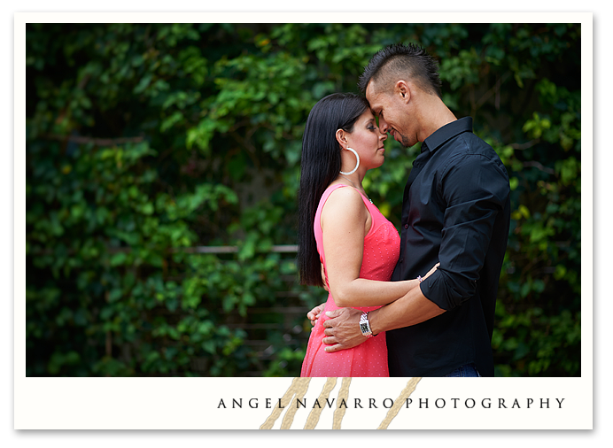 Photo of couple posed in front of grass wall.