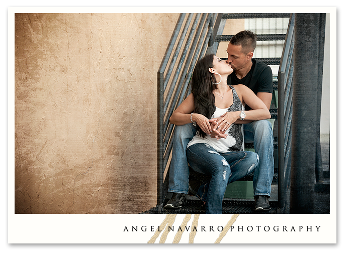 Engaged couple kissing on a stairwell.
