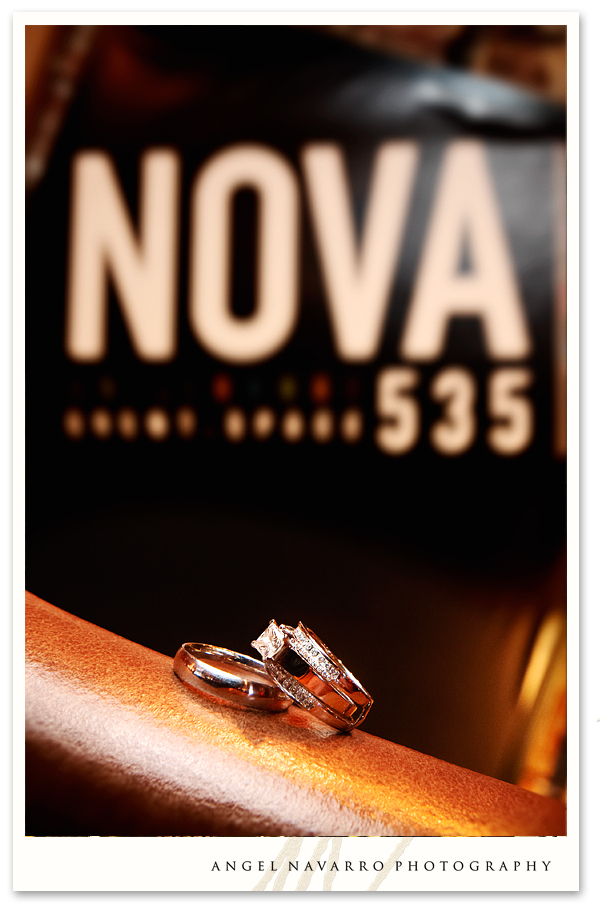 A creative photo of the wedding rings in front of a NOVA535 poster