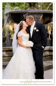 A beautiful wedding portrait of the bride and groom by a fountain.