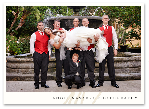 Wedding party holds bride up in the air during wedding picture.