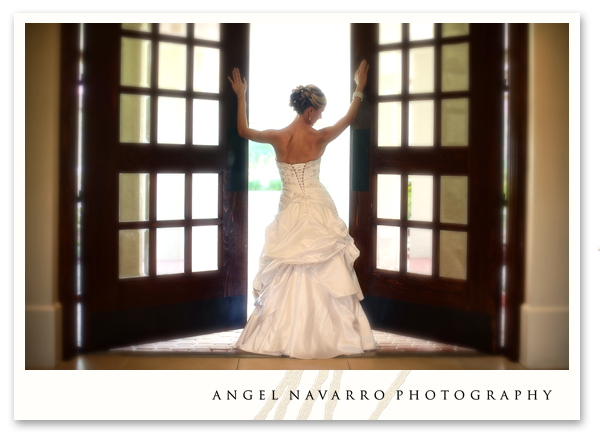 A bride stands at the threshold of a doorway.