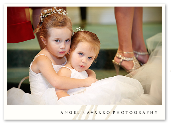 Wedding Photography - Two small bridesmaids sit on the steps of the altar during the ceremony.